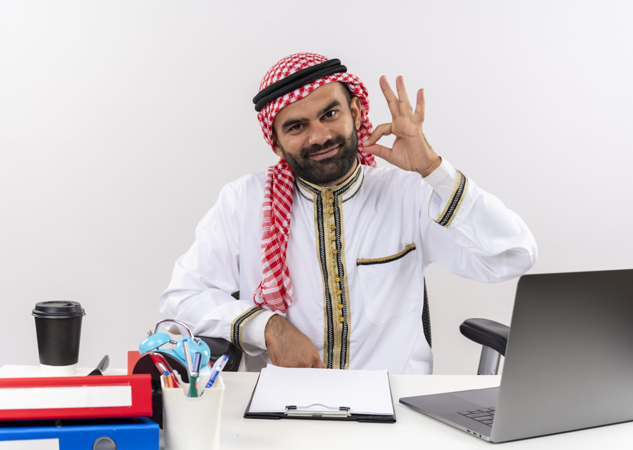 arabic businessman traditional wear sitting table with laptop computer happy positive doing ok sign working office